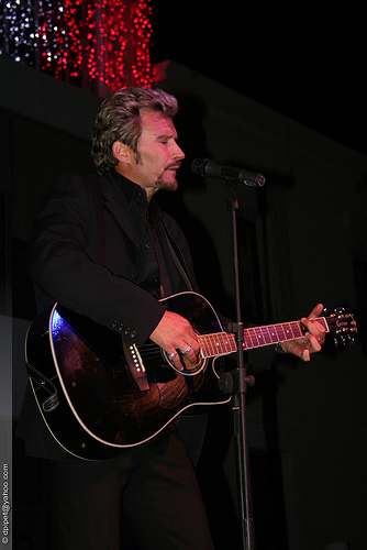 Johnny joue de la guitare, en Concert  Costume noir,  �  Le Rock , quoiqu'il vient de sortir un nouvel album Coffrets CD�A D&eacute;couvrir!!